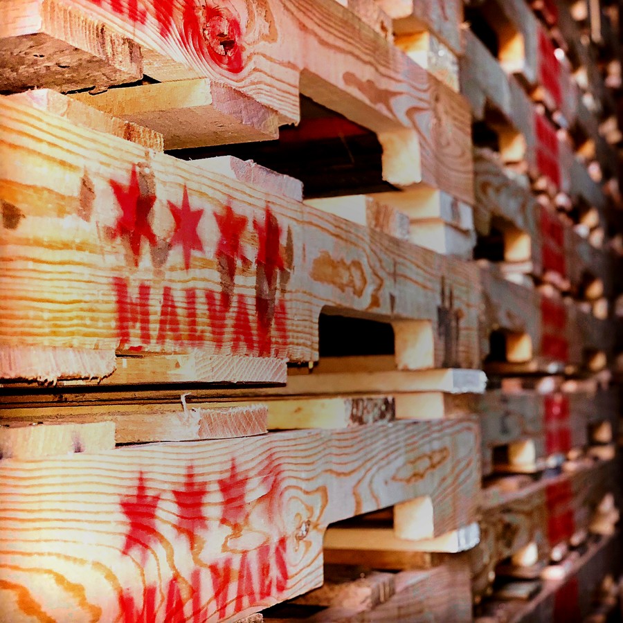 Close-up of stacked Malvaes wooden pallets with red Chicago stars and MALVAES stencils